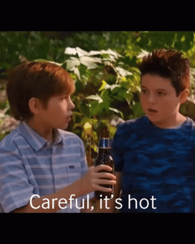 Two Young Boys Standing Next To Each Other With One Holding A Bottle Of Beer And The Words Careful It 'S Hot Above Them GIF