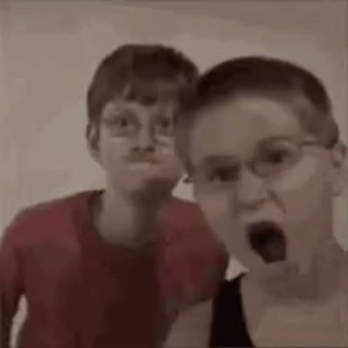 Two Young Boys Wearing Glasses Are Making Funny Faces . GIF