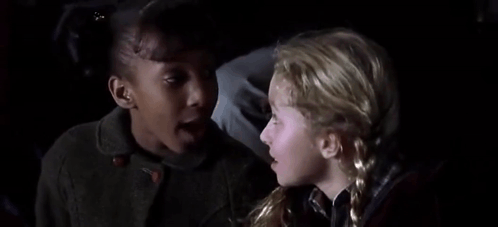 Two Young Girls Sitting Next To Each Other In Dark Room GIF