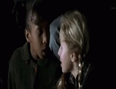 Two Young Girls Sitting Next to Each Other in Dark Room