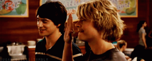 Two Young Men Are Giving Each Other A High Five GIF