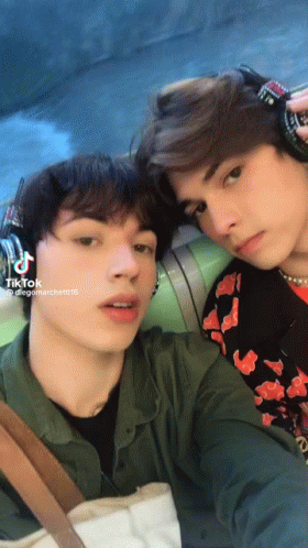 Two Young Men Are Posing For A Picture And One Of Them Has Tiktok Written On His Phone GIF