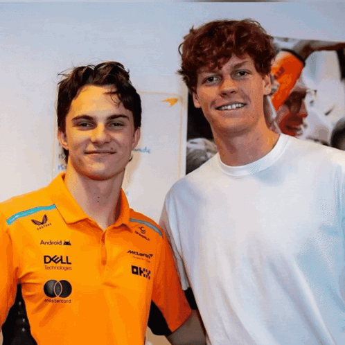 Two Young Men Are Posing For A Picture With One Wearing An Orange Shirt That Says Dell GIF