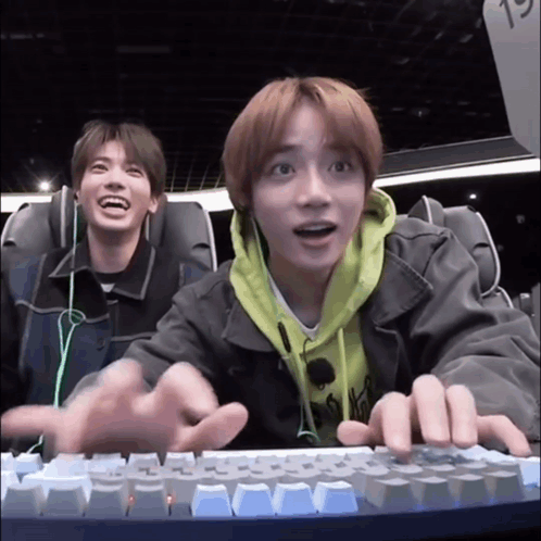 Two Young Men Are Sitting In A Roller Coaster And Playing A Video Game On A Keyboard . GIF