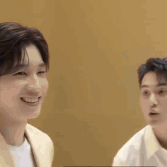 Two Young Men Are Sitting Next To Each Other And Smiling At Each Other . GIF