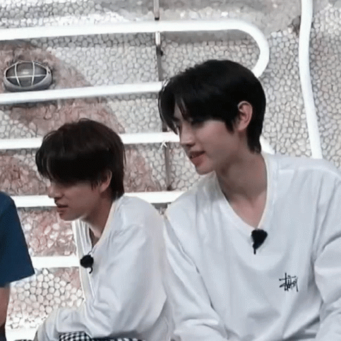 Two Young Men Are Sitting Next To Each Other In A Room . GIF