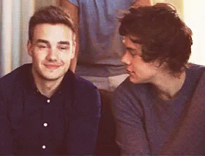 Two Young Men Are Sitting Next To Each Other On A Couch And Looking At Each Other . GIF
