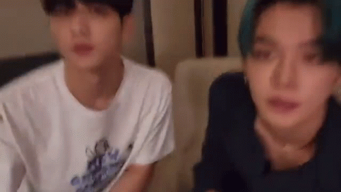 Two Young Men Are Sitting Next To Each Other On A Couch And Looking At Each Other . GIF
