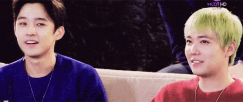 Two Young Men Are Sitting Next To Each Other On A Couch And One Has Green Hair GIF