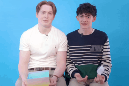 Two Young Men Are Sitting Next To Each Other With One Wearing A Sweater That Says Jw On It GIF