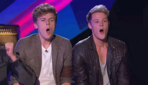 Two Young Men Are Sitting Next To Each Other With Their Mouths Open . GIF