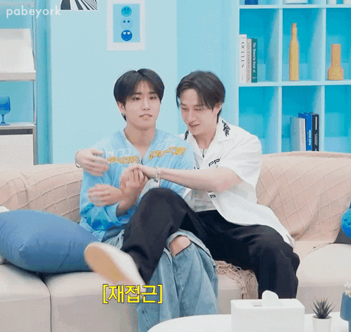 Two Young Men Are Sitting On A Couch And One Of Them Is Wearing A Blue Shirt That Says ' Ff ' On It GIF