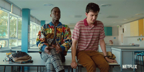 Two Young Men Are Sitting On A Table With A Netflix Logo In The Corner GIF