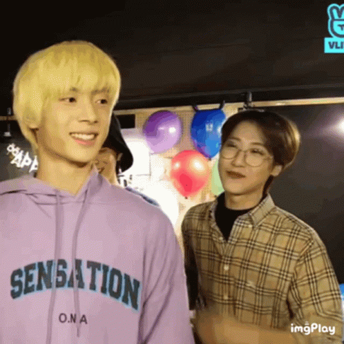 Two Young Men Are Standing Next To Each Other And One Of Them Is Wearing A Purple Hoodie That Says Sensation On It . GIF