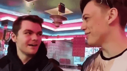 Two Young Men Are Standing Next To Each Other In A Diner Talking To Each Other . GIF