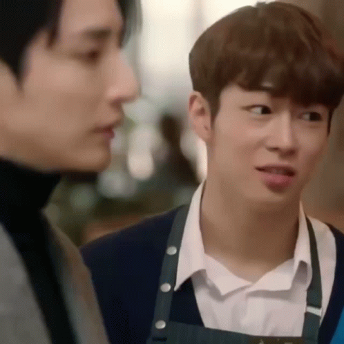 Two Young Men Are Standing Next To Each Other In A Restaurant . GIF