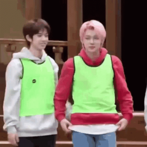 Two Young Men Are Standing Next To Each Other In A Room . GIF