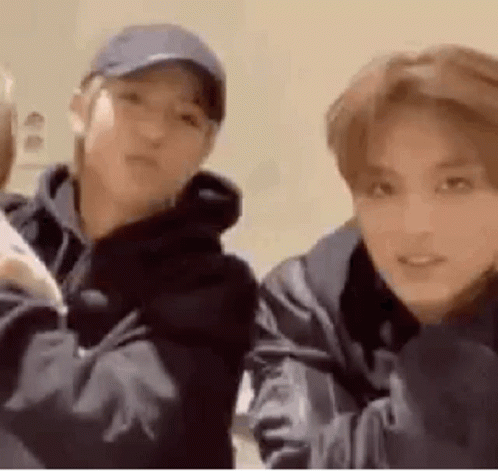 Two Young Men Are Standing Next To Each Other In A Room . One Of The Men Is Wearing A Baseball Cap . GIF