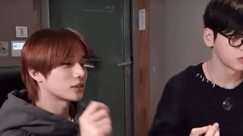 Two Young Men Are Standing Next To Each Other In A Room . GIF