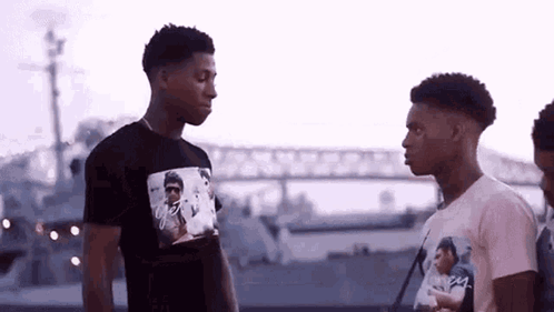 two young men are standing next to each other in front of a boat .