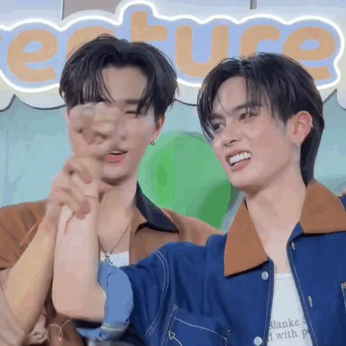 Two Young Men Are Standing Next To Each Other In Front Of A Sign That Says Ecture GIF