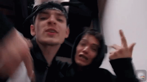 Two Young Men Are Standing Next To Each Other Making A Peace Sign . GIF