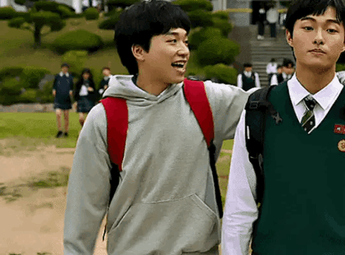 Two Young Men Are Standing Next To Each Other On A Sidewalk . GIF