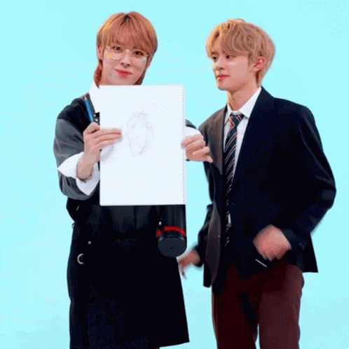 Two Young Men Are Standing Next To Each Other One Is Holding A Drawing GIF