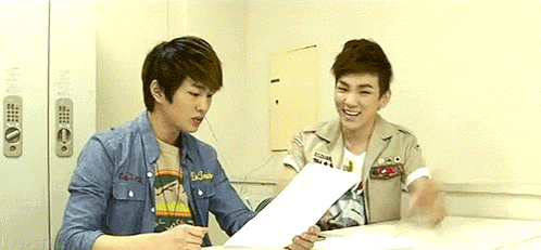 Two Young Men at Table Looking at Papers