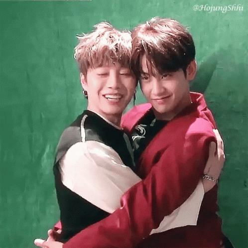 Two Young Men Hugging Each Other With A Green Background GIF