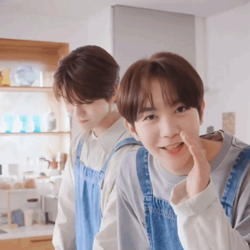Two Young Men In Aprons Standing Together GIF