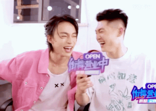 Two Young Men Laughing With Open Sign