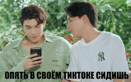 Two Young Men Looking at Cell Phone With Foreign Caption