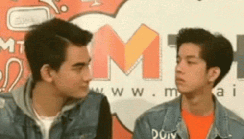 Two Young Men Looking at Each Other in Front of M1 Sign