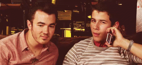 Two Young Men on Couch One on Phone