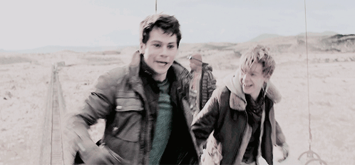 Two Young Men Running In Desert Holding Hands GIF