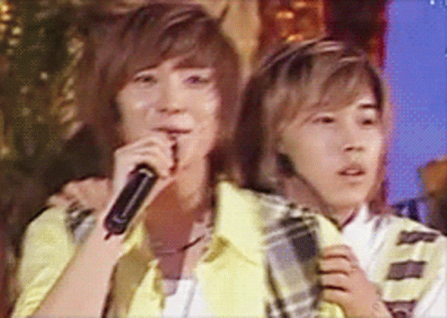Two Young Men Singing Into Microphones While One Has A Headset On GIF