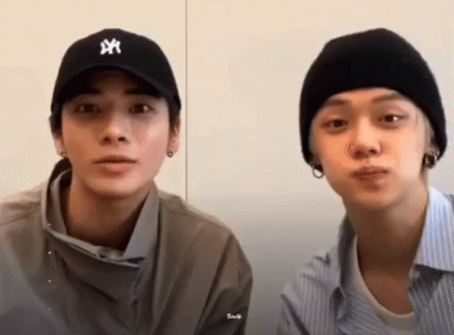 Two Young Men Sitting Next To Each Other Wearing Hats GIF