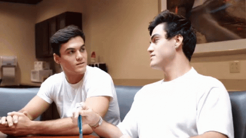 Two Young Men Sitting With Crossed Arms GIF