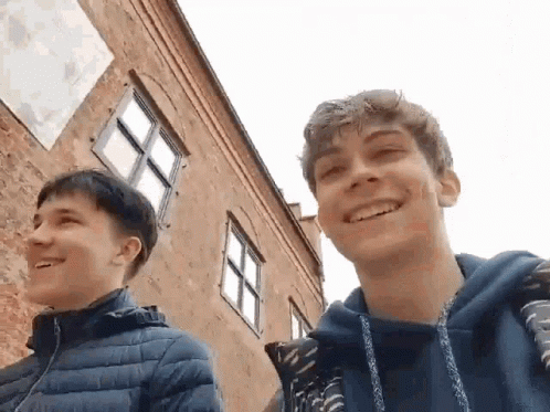 Two Young Men Smiling by Brick Building