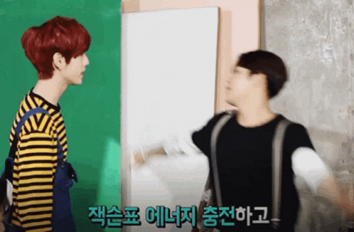 Two Young Men Standing in Front of Green and White Wall One Red Hair One Blonde
