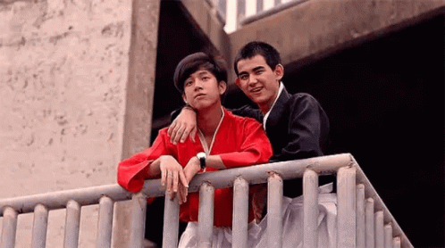 Two Young Men Standing on Railing