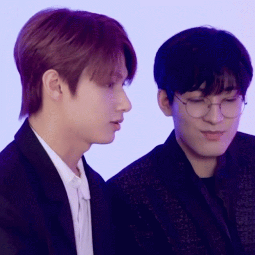 Two Young Men Wearing Glasses Are Sitting Next To Each Other And Looking At Something . GIF