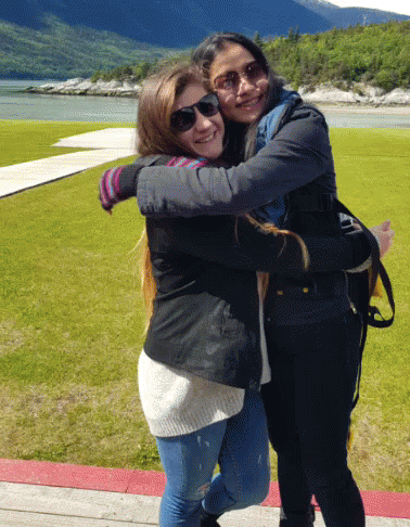 Two Young Women Hugging in Front of Lake