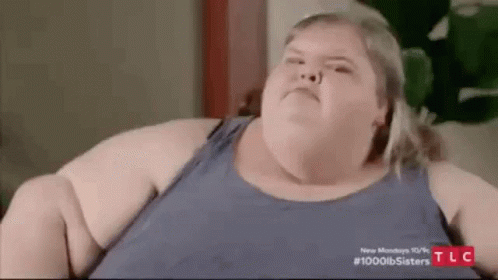 Very Fat Woman Sitting On Couch Looking At Camera GIF