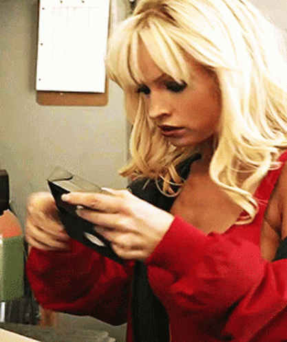 Confused Pamela Anderson Looking At Vhs Tape GIF
