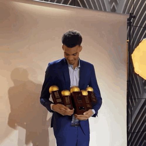 Victor Wembanyama Holding Several Trophies GIF