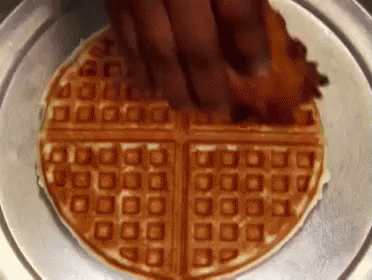 Waffle With Bacon Being Spread On Plate