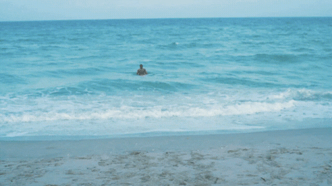 Man Soaking On Beach On A Harmoniously Waves GIF