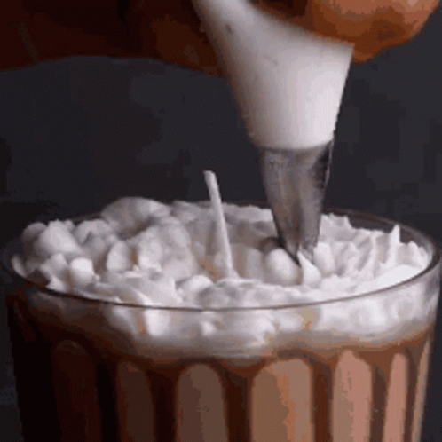Whipped Cream Is Being Poured Into A Glass With A Piping Bag . GIF